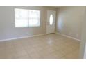 Bright living room with large window, white door, neutral walls, and neutral tiled flooring at 17236 Spring Valley Rd, Dade City, FL 33523
