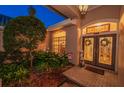 Charming entrance area featuring double doors, a stained glass accent, and a garden area with mature plantings at 1802 Oak Ridge Rd, Safety Harbor, FL 34695