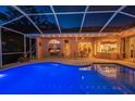 Enjoy Florida evenings in this screened in patio with large pool illuminated with blue light and an entertaining space at 1802 Oak Ridge Rd, Safety Harbor, FL 34695