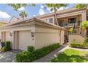 Exterior view of condo featuring a one-car garage and stairs leading to the upper level at 3044 Red Oak Ct # 204, Palm Harbor, FL 34684