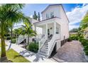 Charming two-story white home with a front porch, showcasing meticulous landscaping and a brick driveway at 340 6Th E St, Bradenton, FL 34208
