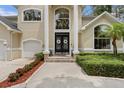 Close up of the impressive front door entrance with towering pillars, updated landscaping, and double doors at 4515 W Leona St, Tampa, FL 33629