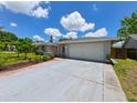 Home featuring a two-car garage and a large driveway surrounded by well-kept landscaping at 6705 Ranger Dr, Tampa, FL 33615