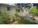 Charming home exterior with a staircase leading to the entrance, surrounded by lush greenery at 7111 Oregon Chickadee Rd, Weeki Wachee, FL 34613
