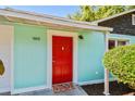 View of the home's inviting red front door, set against a turquoise exterior, creating a vibrant welcome at 905 8Th Sw Ave, Largo, FL 33770