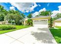 Spacious home with a large driveway, three-car garage, and a well-manicured lawn and blue sky at 12435 Oak St, San Antonio, FL 33576