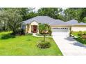 Lovely home with a well-maintained lawn, mature trees, and a three-car garage, and a welcoming red door at 12435 Oak St, San Antonio, FL 33576