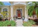 Charming front entrance with red door, decorative wreath, and inviting walkway with garden plants at 12435 Oak St, San Antonio, FL 33576