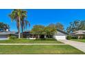 Well-maintained single-story home featuring lush landscaping, a green lawn, and an attached two-car garage at 1622 El Tair Trl, Clearwater, FL 33765