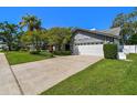 Well-maintained home featuring lush landscaping, a driveway, and an attached two-car garage at 1622 El Tair Trl, Clearwater, FL 33765