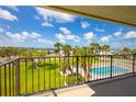 Balcony view of the pool area with lush green lawns and palm trees at 2530 Gary Cir # 301, Dunedin, FL 34698