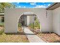 Charming front entrance features an arched gate, stucco walls, and landscaped walkway at 3041 Waterfall Dr, Spring Hill, FL 34608