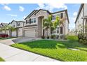 Beautiful two-story home with manicured lawn and a paver driveway leading to the garage at 3071 Marine Grass Dr, Wimauma, FL 33598