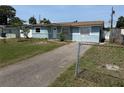 A blue house with a modest front lawn and a driveway, seen from behind a chain link fence at 4506 Eden Rock Rd, Tampa, FL 33634