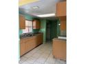 Traditional kitchen featuring light-colored cabinets, tile floors, and a double sink beneath a window at 4506 Eden Rock Rd, Tampa, FL 33634