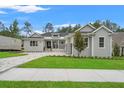 Well-manicured lawn and landscaping accentuate this modern gray home with a welcoming front porch at 4522 Majestic Hills Loop, Brooksville, FL 34601