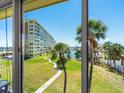 Scenic view from the balcony overlooking a grassy lawn, trees, and a glimpse of the waterway in the distance at 4700 Cove Cir # 301, St Petersburg, FL 33708