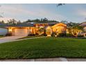 Charming single story home featuring mature landscaping, a tile roof, and a two-car garage at twilight at 5027 Cross Pointe Dr, Oldsmar, FL 34677