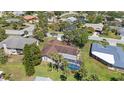 Aerial view of home with enclosed pool, screened-in lanai, lush landscaping, and neighboring houses at 5507 Nimitz Rd, New Port Richey, FL 34652