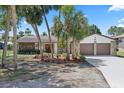 Charming single-Gathering home featuring an attached two-car garage, stone accents, landscaped yard with palm trees, and a driveway at 5507 Nimitz Rd, New Port Richey, FL 34652