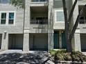 Exterior of condominium featuring garage, balcony, teal front door and mature landscaping at 622 Seascape Way, Tampa, FL 33602