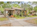 Quaint home exterior featuring a carport, lovely landscaping, and a cozy front porch, adding character to the property at 916 E Broad St, Tampa, FL 33604