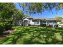 Landscaped front yard with lush green lawn and mature trees shading a gray single story home at 10716 Ashford Oaks Dr, Tampa, FL 33625