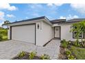 Modern home showcasing clean white facade, neat landscaping, and a paved walkway leading to the front door and attached garage at 12106 Clarendon Ave, Port Charlotte, FL 33981