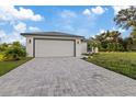 Inviting single-story home with a manicured lawn, gray roof, and a spacious paved driveway leading to an attached garage at 12106 Clarendon Ave, Port Charlotte, FL 33981