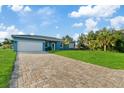 Wide paved driveway leads to a charming blue home with well-maintained lawn and lush landscaping at 12486 Gulfstream Blvd, Port Charlotte, FL 33981