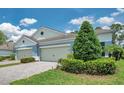 Charming home with a two-car garage and lush landscaping featuring bushes and an evergreen tree at 12817 Cobalt Ter, Bradenton, FL 34211