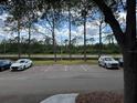Parking lot with lined spaces, tall pines, a pond, and views of mature landscaping at 13243 Sanctuary Cove Dr # 204, Temple Terrace, FL 33637