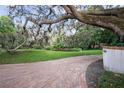 Brick driveway leads to a charming property with lush green lawns and mature trees at 14825 Lake Magdalene Cir, Tampa, FL 33613