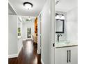 Hallway showcasing hardwood floors, half bathroom, and access to a cozy living room with fireplace at 2033 Arbor Dr, Clearwater, FL 33760