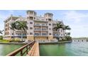 Stunning waterfront condo building with a private dock, balconies, and lush tropical landscaping at 205 Brightwater Dr # 101, Clearwater Beach, FL 33767
