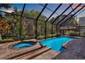 Relaxing screened-in pool and spa area with lush greenery, perfect for outdoor enjoyment at 2614 Brookforest Dr, Wesley Chapel, FL 33544