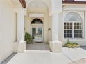Elegant double door entry with decorative glass, flanked by white pillars and manicured plants at 3610 Woodbridge Ave, North Port, FL 34287