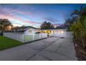 Charming single-story home featuring a long driveway and a classic white picket fence at dusk at 4709 W Fair Oaks Ave, Tampa, FL 33611