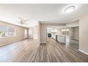 Open concept living space with wood-look floors, ceiling fan, and a view of the modern kitchen at 6241 Ansley St, Spring Hill, FL 34606