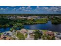 Aerial view of a home with water access and view of a nearby school on a sunny day at 699 Merlins Ct, Tarpon Springs, FL 34689