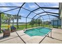 Screened-in pool area with a waterfall feature and views of the lush green lawn at 764 W Bayshore Dr, Tarpon Springs, FL 34689