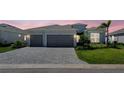 Stunning home showcases a paver driveway, a two-car garage, and lush landscaping at 8589 Saint Kitts Cir, Englewood, FL 34224