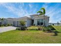Beautiful single-story home featuring a two-car garage, paver driveway, manicured lawn, and tropical landscaping at 8589 Saint Kitts Cir, Englewood, FL 34224