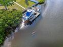 Aerial view of boat and dock near lush shoreline with sunlit river, highlighting waterfront property at 925 Eagle Ln, Apollo Beach, FL 33572