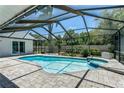 Enjoy this screened in pool with a spa, covered with brick pavers, and clear blue skies at 1028 Wyndham Way, Safety Harbor, FL 34695