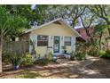 Quaint yellow home boasts a teal door, complemented by lush landscaping and a welcoming walkway at 132 21St S Ave, St Petersburg, FL 33705