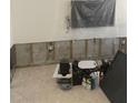Living room ready for renovation with exposed concrete walls, tile floor, and a TV covered in plastic at 3514 Gulf # 2, St Petersburg, FL 33706