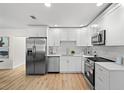 Modern kitchen features white cabinets, stainless steel appliances, tiled backsplash, and wood look flooring at 4549 Ontario Dr, New Port Richey, FL 34652