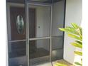 Screened entryway featuring unique tile design and a wooden door with an oval glass insert at 50 Water Oak Way, Oldsmar, FL 34677