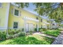 Bright yellow townhome with white trim, well-maintained landscaping, and a pergola over the entrance walkway at 5042 Coquina Key Se Dr, St Petersburg, FL 33705